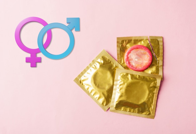 Foto wereld seksuele gezondheid of aids dag condoom in verpakking scheur open en mannelijke vrouwelijke geslacht tekens