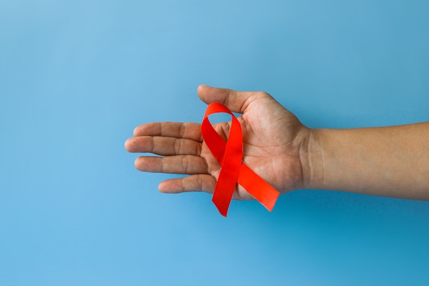 Wereldaidsdag en Werelddiabetesdag met mannelijke handen met rood aids-bewustzijnslint geïsoleerd