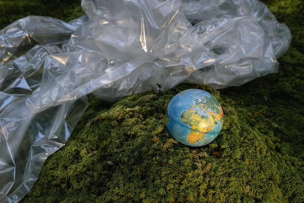 Foto wereldbol en plastic folie groen bos, vervuiling van het milieu. het probleem van het recyclen van plastic