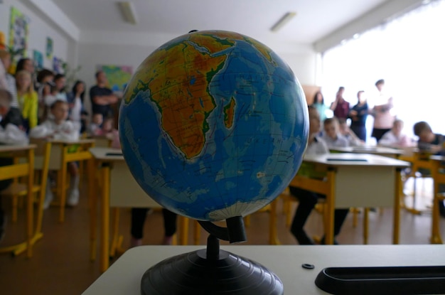 Wereldbol op een bureau voor schoolkinderen in een klaslokaal tijdens een open les