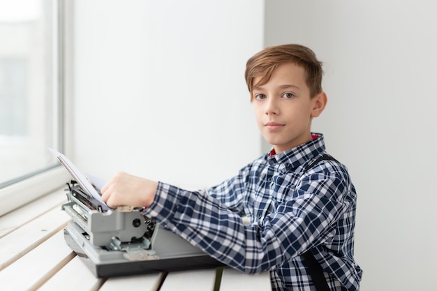 Werelddag van de schrijver-concept - Jongen met een oude typemachine over vensterachtergrond.