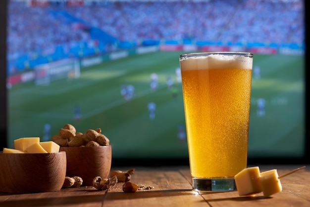 Wereldkampioenschap voetbal kijken op een grote tv met een glaasje bierpinda's en kaas