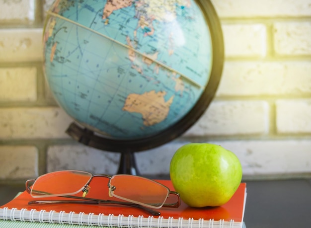 Foto wereldlerarendag op school stilleven met boeken globe apple bril zonlicht