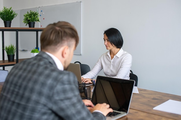 Werk in een kantoor een vrouw zit tegenover een man tekst te typen