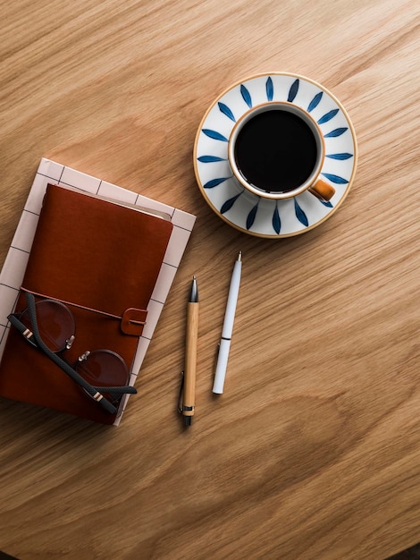 Werk kantoor koffiepauze kopje koffie leren planner bril pen op houten tafel top view