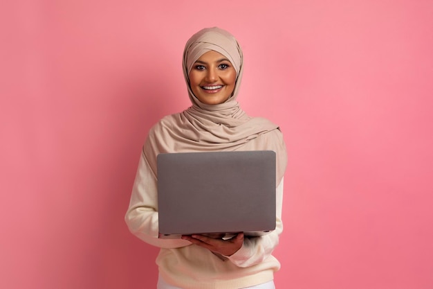 Werk op afstand concept gelukkige moslimvrouw in hijab met laptopcomputer