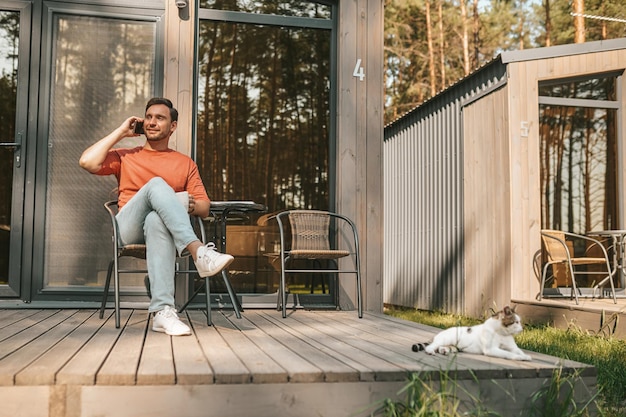 Werk op afstand. Een jonge man die buiten zit te telefoneren