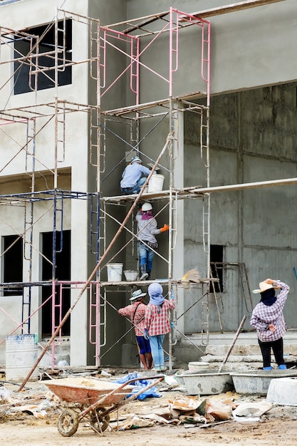 Werk op hoogte, bouwvakkers worden gepleisterd op de steiger op de bouwplaats.
