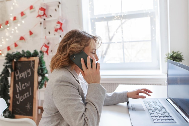 Werk thuis een meisje thuis met een laptop op afstand werken in de kerstwinkel op de bank in vakanties