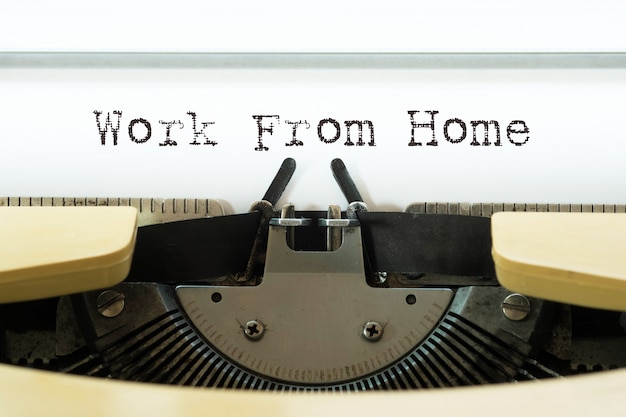 Werk vanuit huis woord getypt op een gele vintage typemachine.