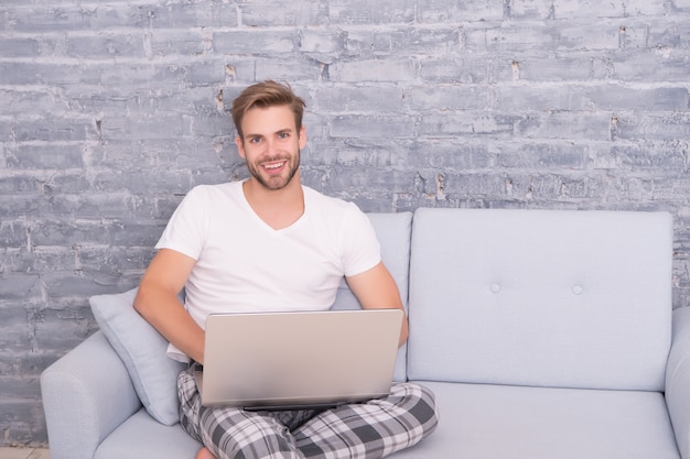 Werk vanuit huis. Zelfisolatie. Blijf thuis. Social distancing. Man werk laptop. Online cursussen. Thuisonderwijs. Online winkelen. Guy gebruikt computer ontspannende bank. Online communicatieconcept.