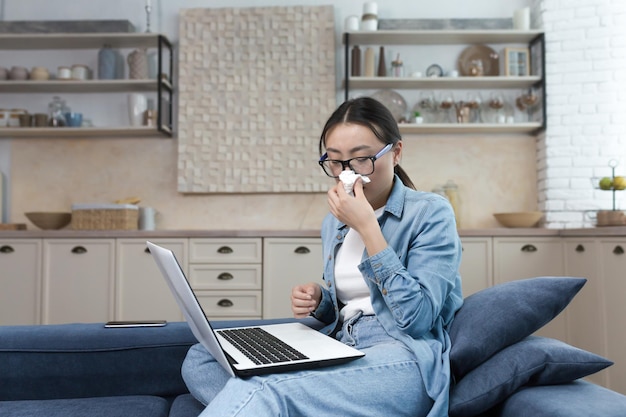 Werk vanuit huis ziekenhuis een jonge Aziatische vrouw freelancer werd ziek werkt vanuit huis op de bank aan de