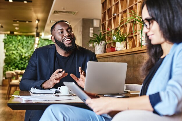 Werk vreugdevol en vredig serieuze vrouw die naar haar collega luistert tijdens de lunch in café