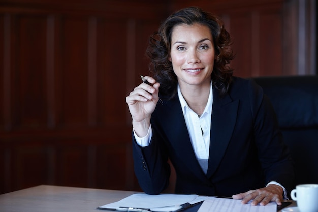 Werken aan een belangrijke zaak Aantrekkelijke vrouwelijke advocaat die aan een bureau zit en aan documenten werkt