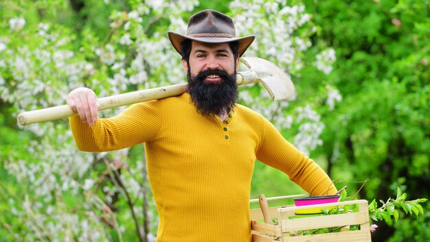 Werken in de tuin bebaarde tuinman met tuingereedschap lachende boer bereidt zich voor op het planten van planten