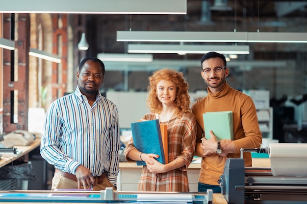 Werken in de uitgeverij. Drie hardwerkende medewerkers die bij een uitgeverij werken, staan samen