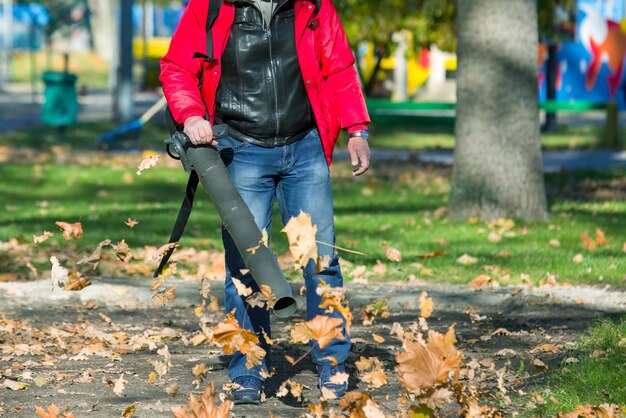 Werken in het Park bladeren verwijderen met een blazer Parkschoonmaakservice Afgevallen bladeren verwijderen in de herfst