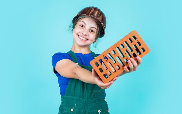 Werken in reparatiewerkplaats. toekomstige ingenieur. gelukkig kind gebruikt baksteen voor renovatiereparatie. bouw bouwplaats. kind architect werknemer. dag van de Arbeid. ontwikkeling van de kindertijd. tiener meisje assistent.