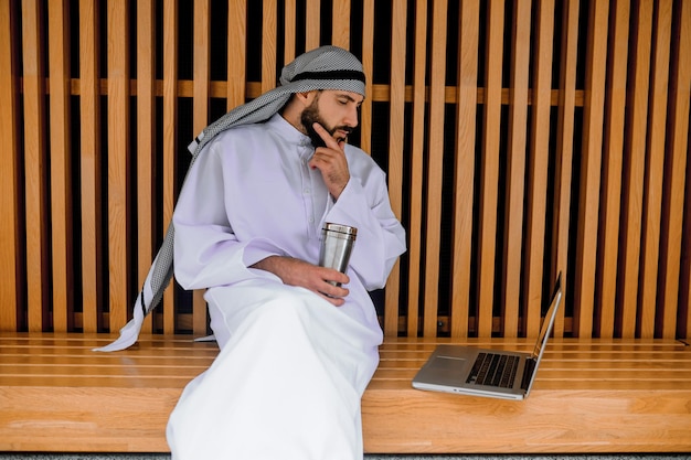 Werken. Jonge Arabische zakenman die op een laptop werkt en er betrokken uitziet