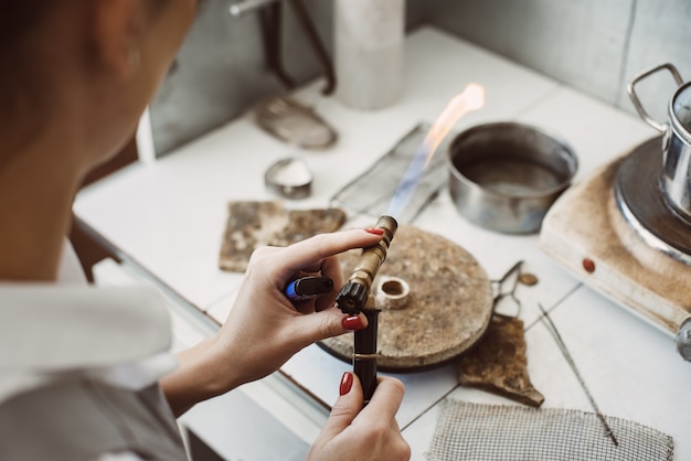 Werken met vuur. Vrouwelijke juwelier handen solderen en lassen zilveren ring op haar workshop sieraden maken. Bedrijf. Sieraden apparatuur. Accessoires