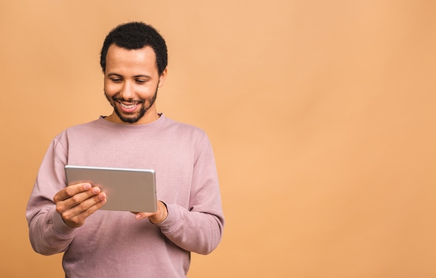 Werken op digitale tablet. Achteraanzicht van jonge man aan het werk op digitale tablet terwijl geïsoleerd over beige.