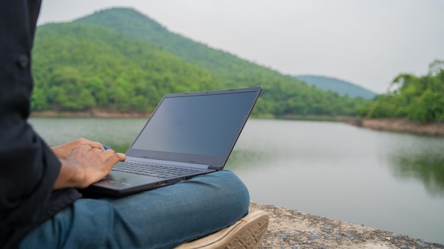 Werken op een laptop en zitten in de natuur Workation en Digital Nomad concept