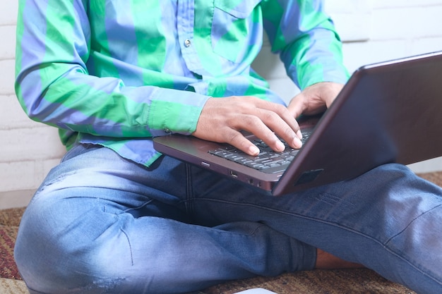 Werken vanuit huis concept, jonge man te typen op de laptop.