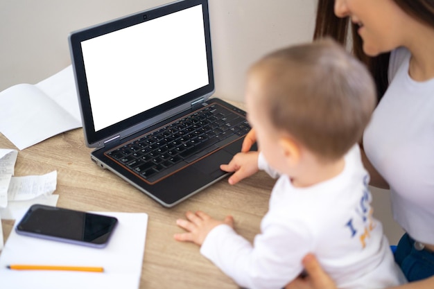 Werkend moederconcept Jonge vrouw die aan laptop met haar kind van huis werkt