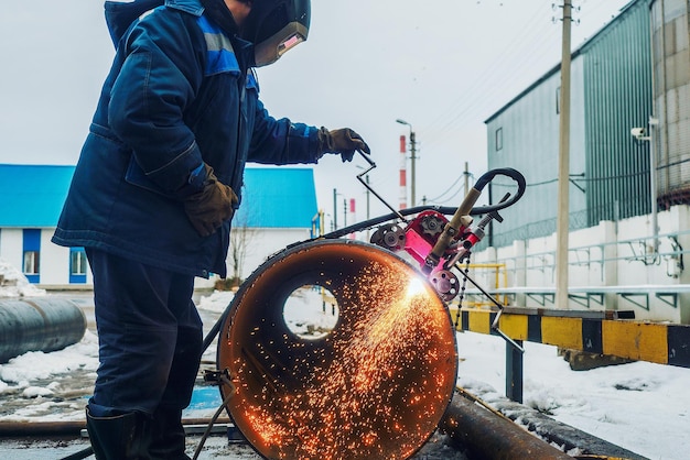 Werkende lasser snijdt metaal en vonken vliegen rond Gassnijden van pijpen met grote diameter met acetyleen en zuurstof Industrieel metaalsnijden in de olie- en gasindustrie