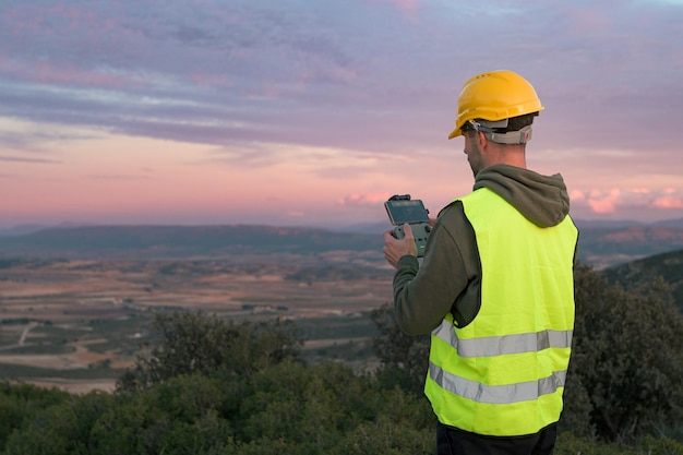 Werkende man regisseert een drone bij zonsondergang