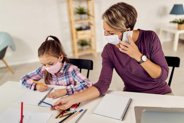 Werkende moeder helpt haar dochter met huiswerk tijdens de COVID19-epidemie