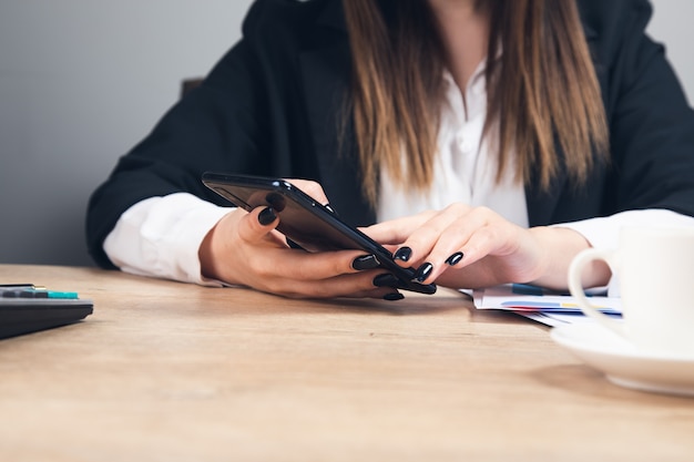 Werkende vrouw handen met behulp van telefoon in office