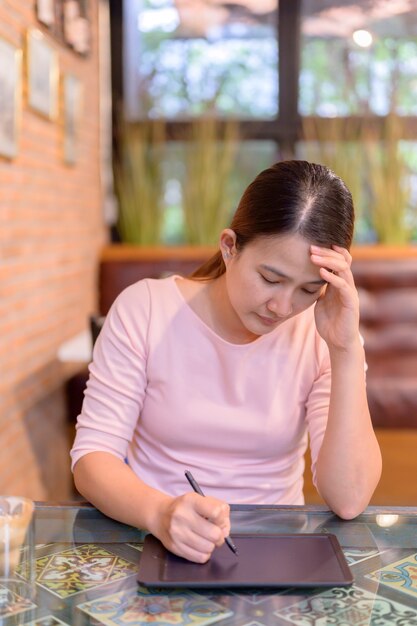 Werkloosheid en geestelijke gezondheidsproblemen. Banenverlies door het coronavirus in Azië. Thaise zakenvrouw op zoek naar nieuwe baan op website. Posttraumatische stressstoornis (PTSS).