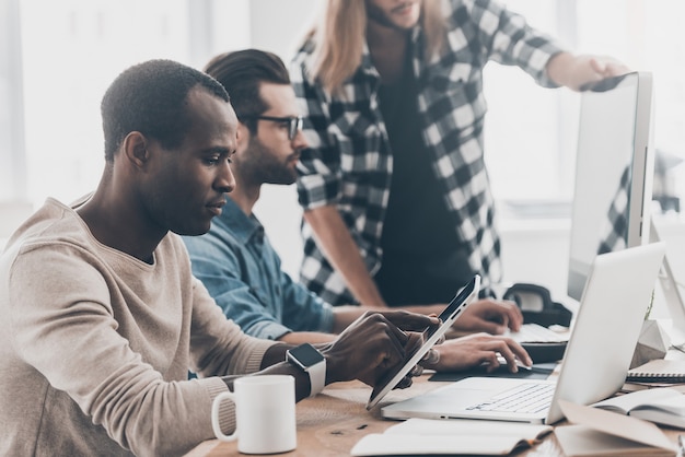 Werkmomenten. Groep jonge zakenmensen die samenwerken en communiceren terwijl ze moderne technologieën gebruiken