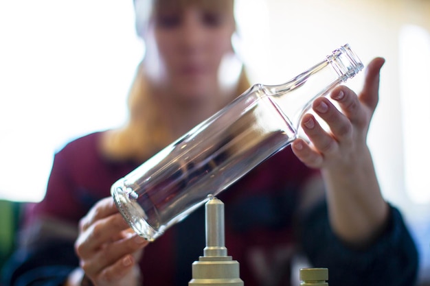 Werkneemster houdt een glazen fles boven het apparaat