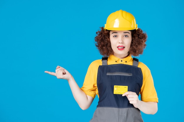 Werkneemster in geel uniform met creditcard op blauw