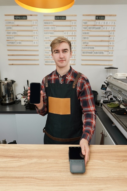 Werknemer barista in schort houdt moderne bankbetaalterminal in café