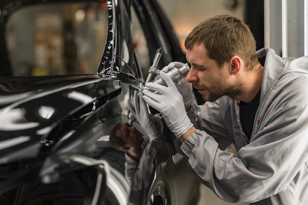 Werknemer carrosserie schilderwinkel controleert de kwaliteit met een microscoop