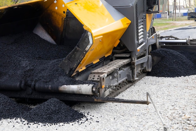 Werknemer die de machine van de asfaltafwerkmachine bedient tijdens de aanleg van wegen en reparatiewerkzaamheden Een afwerking van de asfaltafwerkmachine