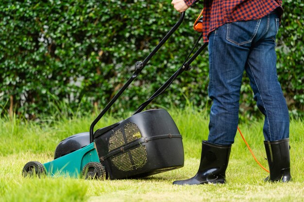 Werknemer die een grasmaaier gebruikt om gras thuis te maaien