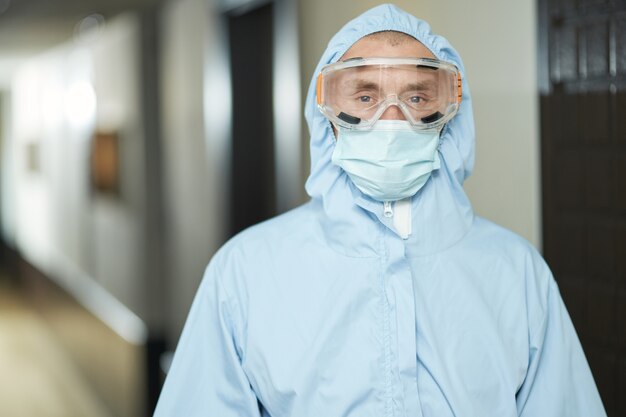 Werknemer die ontsmetting maakt terwijl hij een hazmat-pak draagt