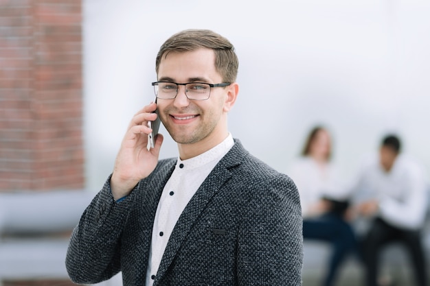 Werknemer die op een smartphone praat terwijl hij in een modern kantoor staat. foto met kopieerruimte