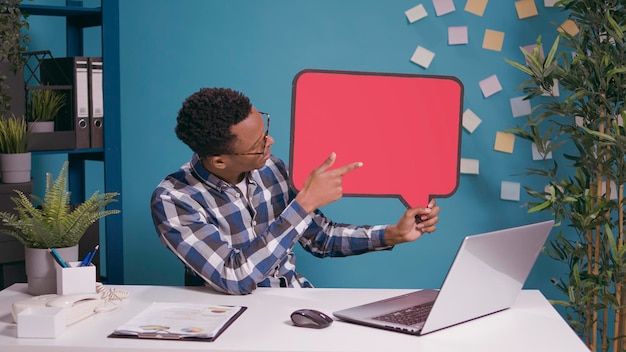 Werknemer die tekstballon gebruikt in een videogesprek op afstand met zakenmensen. Jonge man die een online videoconferentiegesprek bijwoont met een leeg kaartbord voor tekstbericht copyspace.