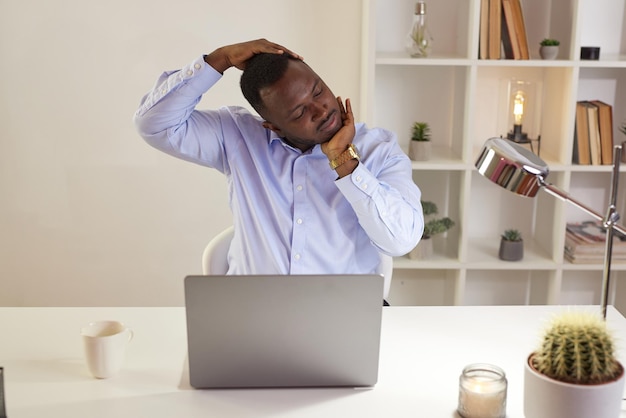 Werknemer die zich uitstrekt op kantoor op het werk moe Afro-Amerikaanse kantoormedewerker