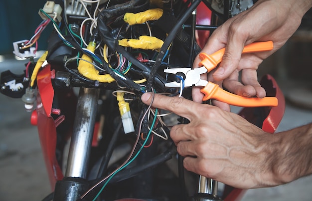 Werknemer elektrische draden afsnijden met een tang.