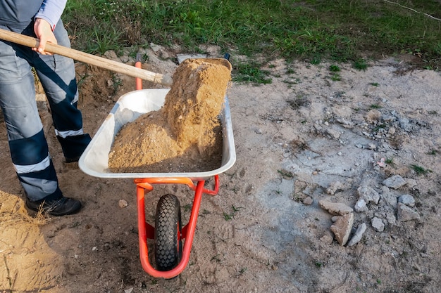 Werknemer giet zand in een kruiwagen