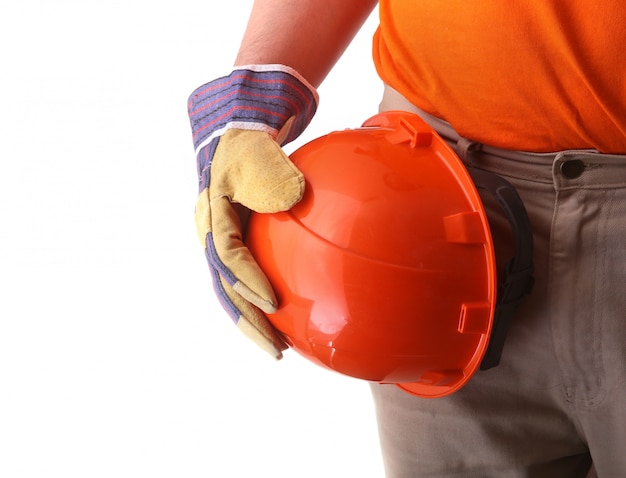 Werknemer in beschermende handschoenen heeft een oranje helm in zijn hand.