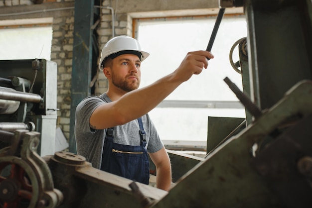 Werknemer in beschermende kleding in fabriek met behulp van machine