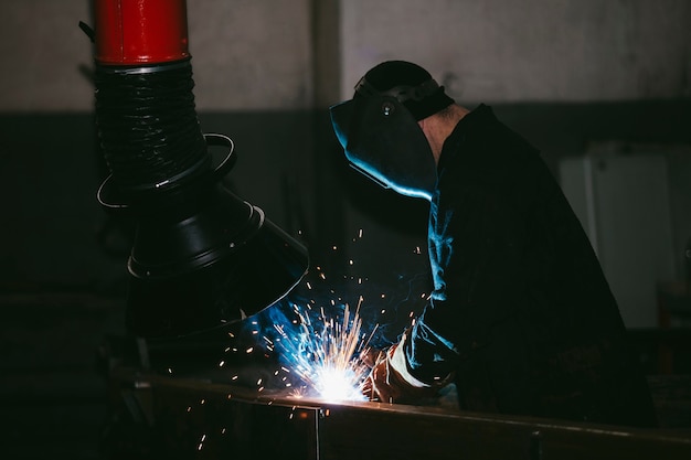 Werknemer in de fabriek in de helm is van ijzer in het lasproces heldere vonken