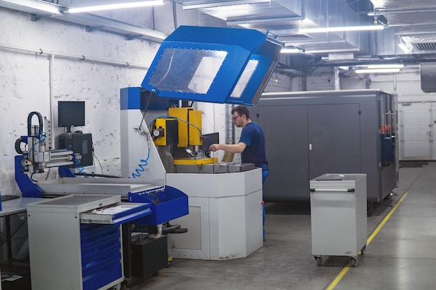 werknemer in de werkplaats regelt de werking van een metaalbewerkingsmachine